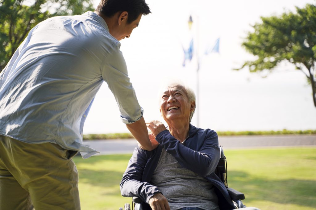 a person touching an old person in a wheelchair